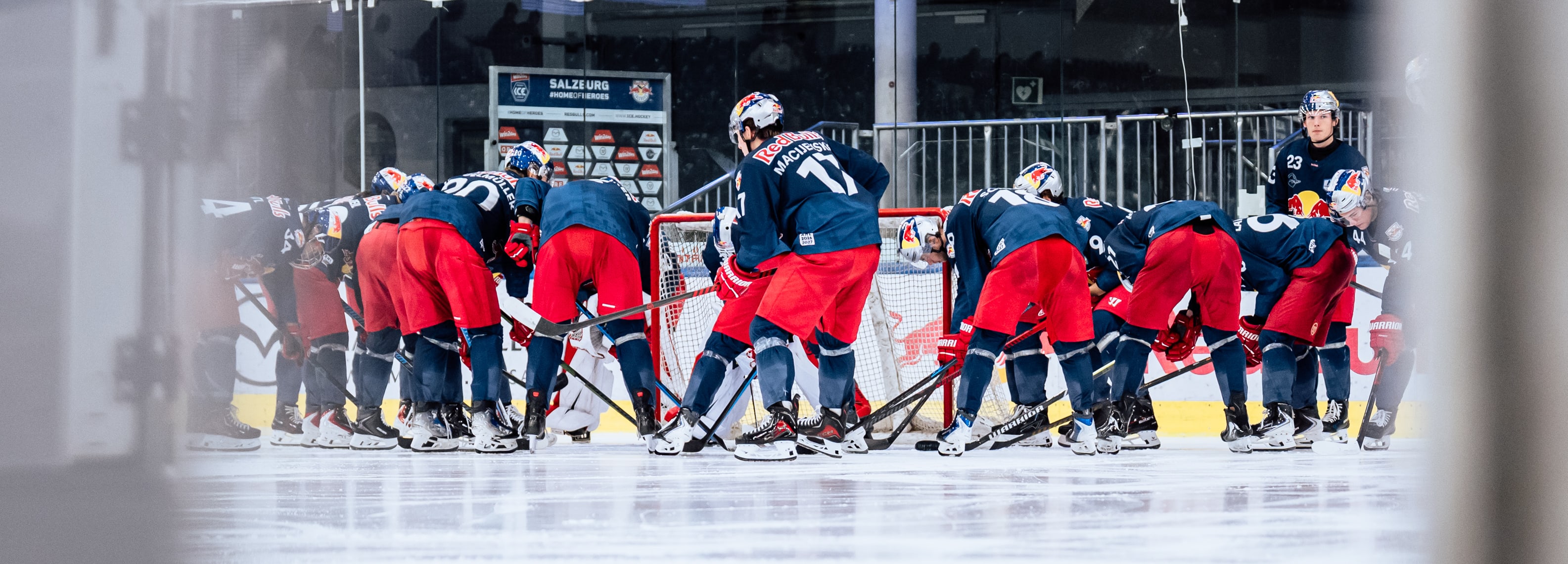 Eishockey-Spieler der Salzburger Red Bulls in roten Hosen und blauen Trikots auf dem Eis