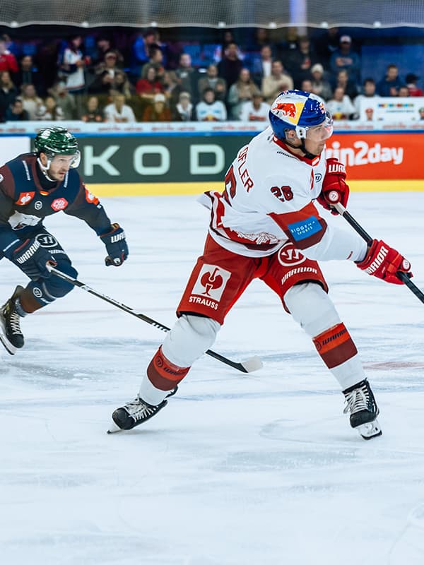 Eishockeyspieler mit Puck auf dem Eis in einer Halle