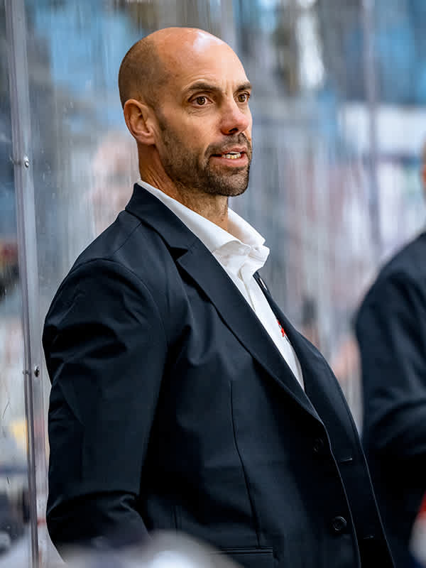Eishockeytrainer Roger Hansson im Anzug mit weißem Hemd im Blick nach rechts.